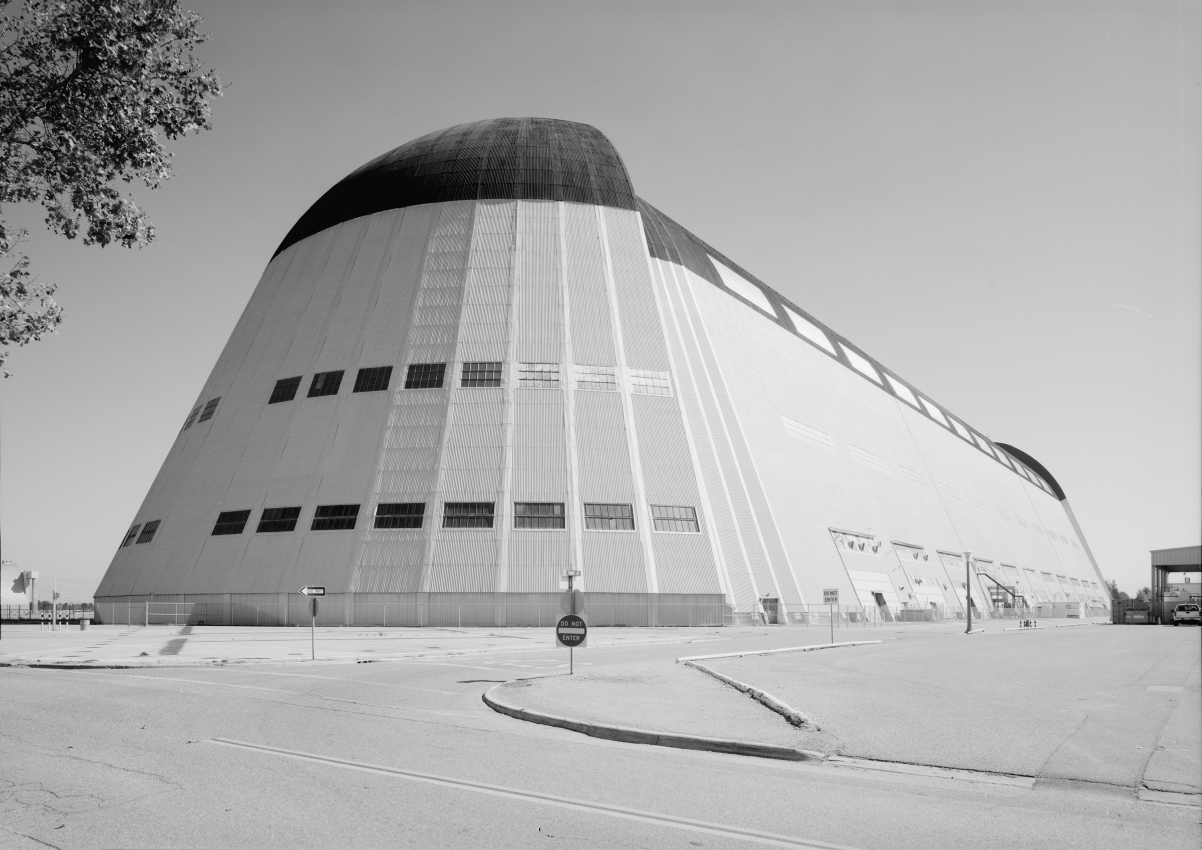 An exterior view of Hangar 1 showing its long, metal facade and the tall, curved doors located at the end of the huge white building.
