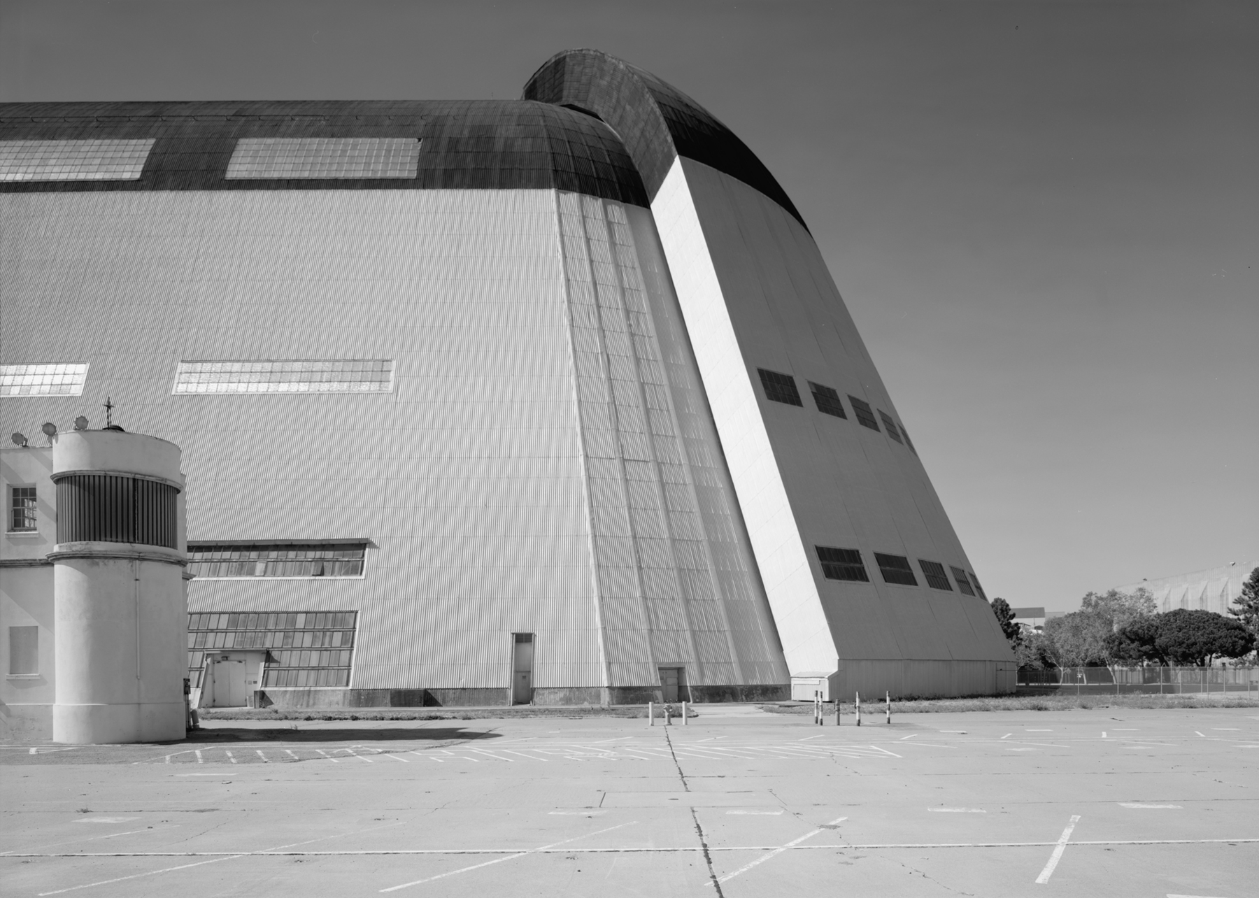 An exterior view of Hangar 1 showing a portion of its long, metal facade and the tall, curved doors located at the end of the huge white building.